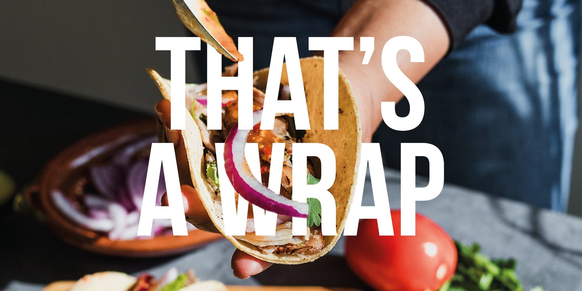 A hand holding a filled wrap, with the words That’s a Wrap